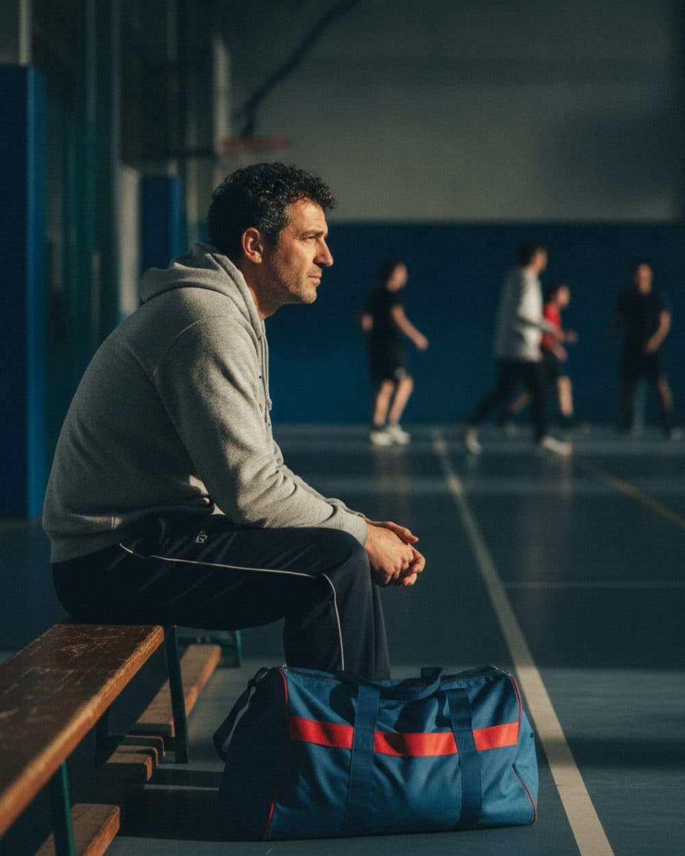 Un pratiquant assis sur un banc au bord du terrain, sac de sport à ses pieds